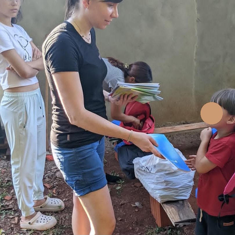 Carmen verteilt Schulhefte an die Kinder