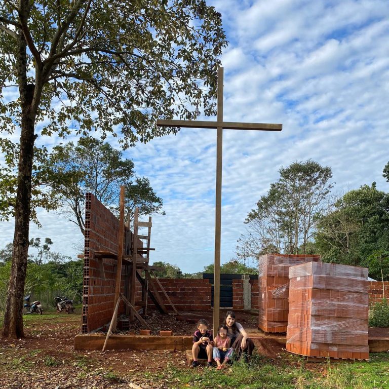 Alexandra und zwei Mädchen sitzen neben einem Holzkreuz